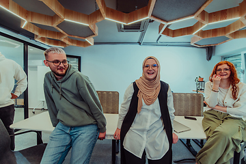 Image showing A group of young business professionals stands together, taking a well-deserved break from their busy workday, showcasing camaraderie, teamwork, and a moment of relaxation in their dynamic workplace