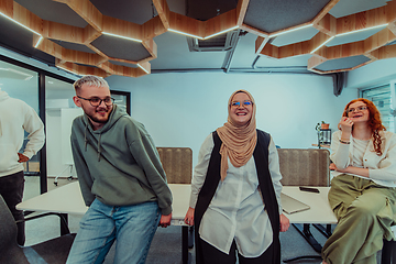 Image showing A group of young business professionals stands together, taking a well-deserved break from their busy workday, showcasing camaraderie, teamwork, and a moment of relaxation in their dynamic workplace