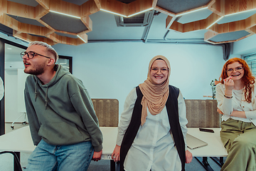 Image showing A group of young business professionals stands together, taking a well-deserved break from their busy workday, showcasing camaraderie, teamwork, and a moment of relaxation in their dynamic workplace