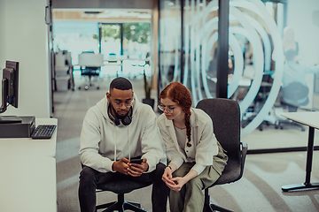 Image showing In a modern office African American young businessman and his businesswoman colleague, with her striking orange hair, engage in collaborative problem-solving sessions