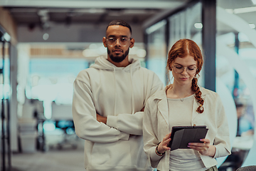 Image showing In a modern office African American young businessman and his businesswoman colleague, with her striking orange hair, engage in collaborative problem-solving sessions