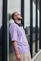 Image showing In front of a modern glass building, a young, blond influencer strikes a confident pose, epitomizing urban glamour and style in the heart of the city