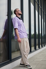 Image showing In front of a modern glass building, a young, blond influencer strikes a confident pose, epitomizing urban glamour and style in the heart of the city