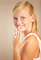 Image showing Woman, happy and wedding ring in studio portrait with smile for proposal, engagement or commitment by background. Girl, model and jewelry for marriage, diamond and metal for celebration at ceremony