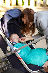 Image showing Mother, baby and pacifier in stroller for walk, together or bonding for exercise, health or wellness. Young woman, infant and giving of dummy for comfort, toddler or child with care in neighborhood