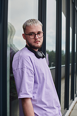 Image showing In front of a modern glass building, a young, blond influencer strikes a confident pose, epitomizing urban glamour and style in the heart of the city