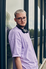 Image showing In front of a modern glass building, a young, blond influencer strikes a confident pose, epitomizing urban glamour and style in the heart of the city