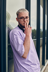 Image showing In front of a modern glass building, a young, blond influencer strikes a confident pose, epitomizing urban glamour and style in the heart of the city