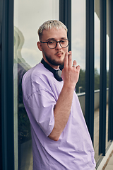 Image showing In front of a modern glass building, a young, blond influencer strikes a confident pose, epitomizing urban glamour and style in the heart of the city