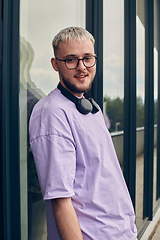 Image showing In front of a modern glass building, a young, blond influencer strikes a confident pose, epitomizing urban glamour and style in the heart of the city