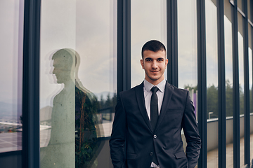 Image showing A CEO dressed in a sleek black suit stands confidently at the entrance of a modern corporate building, awaiting the start of the workday in the bustling urban environment.