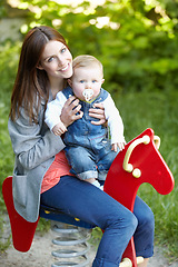 Image showing Portrait, mother and baby with toy, horse and park for fun in bond by playing for outside together. Happy woman, infant or smile for milestone, future growth or development with love, support or care