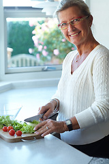 Image showing Portrait of senior woman on chopping board, vegetables and knife in kitchen cooking food. Happy person in glasses cutting plants on counter, lettuce and tomatoes, nutrition and healthy diet in home