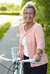 Image showing Portrait, smile and senior woman on bike outdoor, exercise and fitness in summer. Happy, elderly person on bicycle in nature or garden for cycling in countryside for body health, travel and glasses