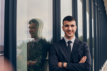 Image showing A CEO dressed in a sleek black suit stands confidently at the entrance of a modern corporate building, awaiting the start of the workday in the bustling urban environment.