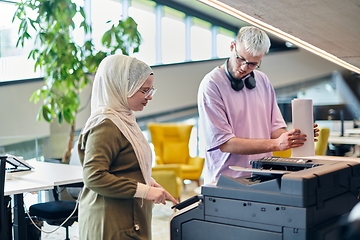 Image showing In a modern startup office, a business-minded Muslim woman wearing a hijab collaborates with her colleague, symbolizing diversity, empowerment, and success in the contemporary corporate world