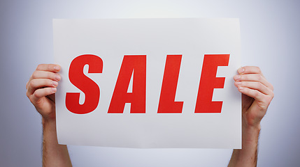 Image showing Sale, sign and hands with a poster, promotion and announcement of discount in studio with white background. Retail, shopping and person advertising with news, banner and deal for commercial savings