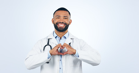 Image showing Portrait, doctor with heart hands and smile in studio for care, kindness and trust icon in healthcare. Support, love emoji and help medical professional man showing happiness on white background.