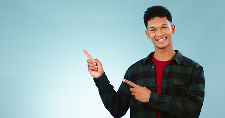 Image showing Portrait, smile and man with hand pointing to studio for mockup, space or news on blue background. Presentation, smile and face of model show information, announcement or menu, guide or how to steps