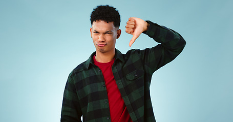 Image showing Thumbs down, frown and portrait of man with hand, vote or bad review on blue background. Unhappy, face or model face with finger emoji for fail, feedback or disappointed by poor, results or rejection