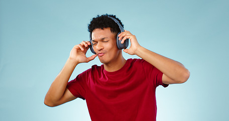 Image showing Man, headphones and dancing with music in studio for mock up of streaming service on blue background. Cape Town, male model and eyes closed for listening to song, podcast or radio in space with promo