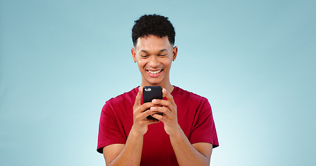 Image showing Man, smile and texting on phone in studio for communication mock up on blue background. Young, person, model and Cape Town with mobile app, message or social media by internet, connection or cellular