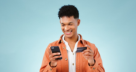 Image showing Man, phone and credit card for online shopping, e commerce and digital money on a blue background. Happy student or young person with mobile app, internet banking or e learning registration in studio