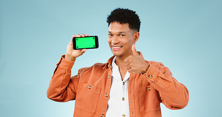 Image showing Thumbs up, green screen phone and portrait of man on blue background for promotion, approval or thank you. Emoji, social media and person with hand sign for agreement, mobile app or website in studio