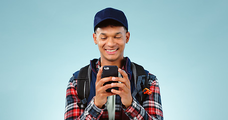 Image showing Hiking, smile and typing with man, smartphone and internet on a blue studio background. Person, hiker and model with a cellphone, mobile user and contact with email, mockup space and website info