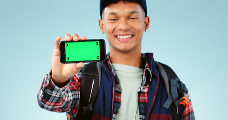 Image showing Hiking, green screen and man with a cellphone, smile and happiness on a blue studio background. Person, hiker and model with adventure, mockup space or smartphone with tracking markers or digital app