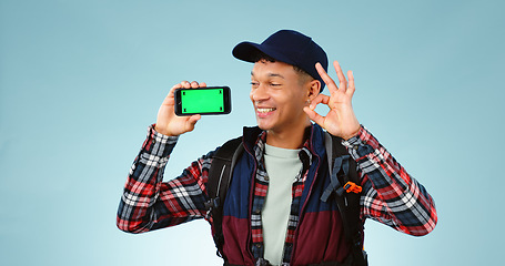 Image showing Hiking, green screen and man with a smartphone, ok sign and happiness on a blue studio background. Person, hiker and model with perfect symbol, agreement and cellphone with tracking markers and smile