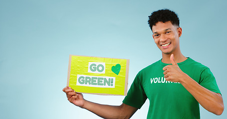 Image showing Man, volunteer and thumbs up with poster in studio on blue background with go green mock up in portrait. Young person, smile or excited for eco friendly, event or recycling in sustainable development