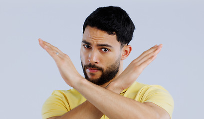 Image showing Portrait, man and cross sign for stop, no and protest for rejection, ban and wrong emoji in studio on white background. Indian model warning of caution, cancel decision and objection to vote