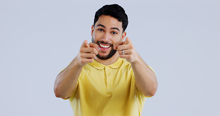 Image showing Man, portrait and smile while pointing to you for decision, choice and vote for winner, volunteer or join us in studio on white background. Indian model show finger for support, emoji and recruitment