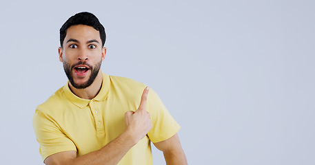 Image showing Man, portrait and pointing up in surprise on mockup for deal, advertising or marketing against a gray studio background. Shocked or surprised male person or model showing notification, alert or sale