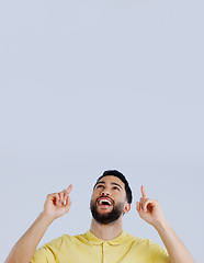 Image showing Man, smile and pointing up to space in studio for advertising choice, decision or launch information on white background. Excited indian model, thinking and show presentation of mockup, ideas or news