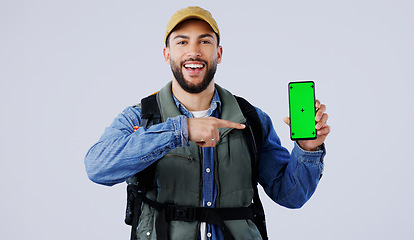 Image showing Happy man, backpack and pointing to phone green screen on mockup or hiking app against a studio background. Portrait of male person or hiker smile and showing mobile smartphone display or travel tips