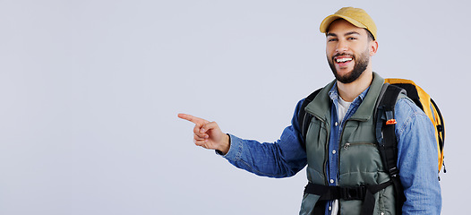 Image showing Happy man, backpack and pointing on mockup for travel, adventure or hiking tips against a studio background. Banner of male person or hiker smile with bag showing trekking list, deal or advertising