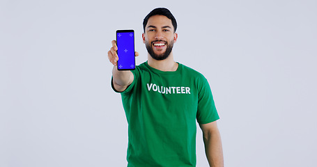 Image showing Happy man, portrait and phone blue screen of volunteer for advertising app against a gray studio background. Male person smile showing mobile smartphone display for community service on mockup space
