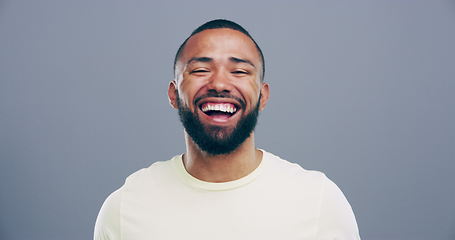 Image showing Face, happy or man laughing at a funny joke or crazy humor in studio isolated on gray background. Freedom, excited model or silly male person with a goofy smile, joy or positive energy to relax alone