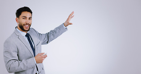 Image showing Portrait, presentation and space with a business man in studio on a gray background for marketing. Smile, speech and information with a happy young corporate employee on mockup for advertising