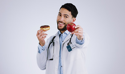 Image showing Man, doctor and smile for apple in portrait, choice and donut or snack options in studio mockup. Happy person, nutritionist and healthy food or approval, advice and opinion or diet by gray background