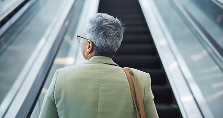 Image showing Woman, back and travel on escalator in airport, building and thinking about work trip opportunity. Mature, businesswoman and walking with luggage and bag on stairs, steps or entrance in lobby