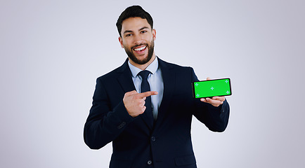 Image showing Business man, phone green screen and pointing to presentation, announcement or news in studio. Portrait of corporate worker with mobile app, career opportunity or website mockup on a white background