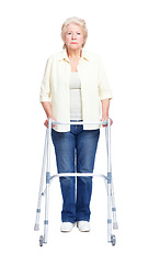 Image showing Overcoming disability. Full-length portrait of a serious elderly woman holding her zimmer frame while isolated on white.