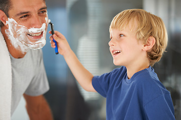 Image showing A good clean shave. A young boy shaving his fathers beard.