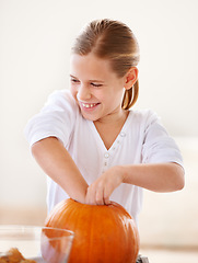 Image showing Hollowing out a pumpkin for a jack-o-lantern. A little girl hollowing out a pumpkin in her kitchen for halloween.