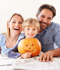 Image showing A family behing their jack-o-lantern. Portrait of a husband and a wife with their son behind a carved pumpkin for halloween.