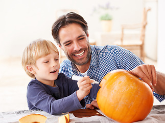 Image showing Wait, one last thing. A father and son marking a pumpkin at home for halloween.