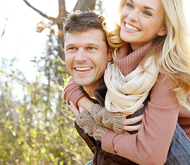 Image showing Having fun in the Autumn sunshine. A happy man piggybacking his girlfriend while spending time in the woods.